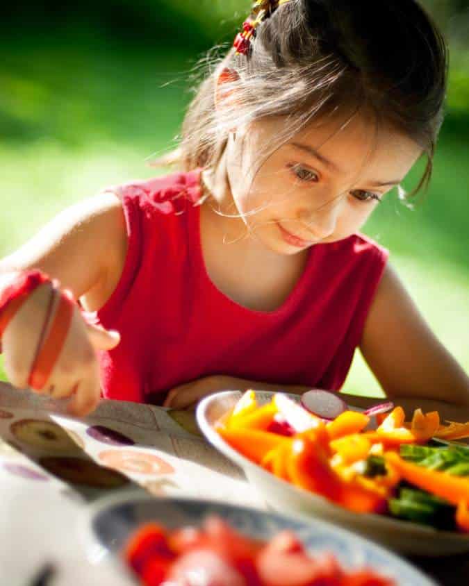 petite fille devant une assiette de légumes