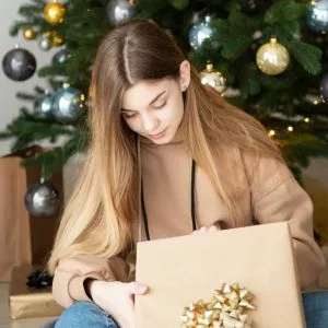 adolescente fille de 15 ans qui ouvre son cadeau de NOël